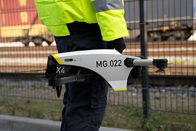 Ein Mitarbeiter von HHLA Sky hält eine Industrie-Drohne am Container Terminal, bereit für Einsätze zur Inspektion oder Bestandsaufnahme.