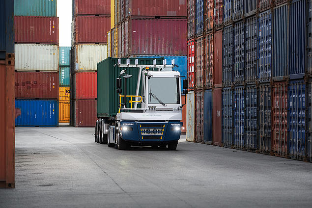 Autonome, elektrisch betriebene Terminalzugmaschine von FERNRIDE fährt durch ein Containerblocklager am HHLA Container Terminal TK Estonia und transportiert einen Container als Teil eines Testprojekts von HHLA Next.