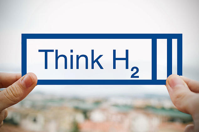 Hands hold a grafic with text “Think H₂” – referring to hydrogen import and distribution within the HHLA network.
