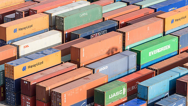 Blick von oben auf ein dicht gestapeltes Containerlager der HHLA mit verschiedenen bunten Frachtcontainern internationaler Reedereien; die Vielfalt an Modellen verdeutlicht das Angebot im Containerhandel.