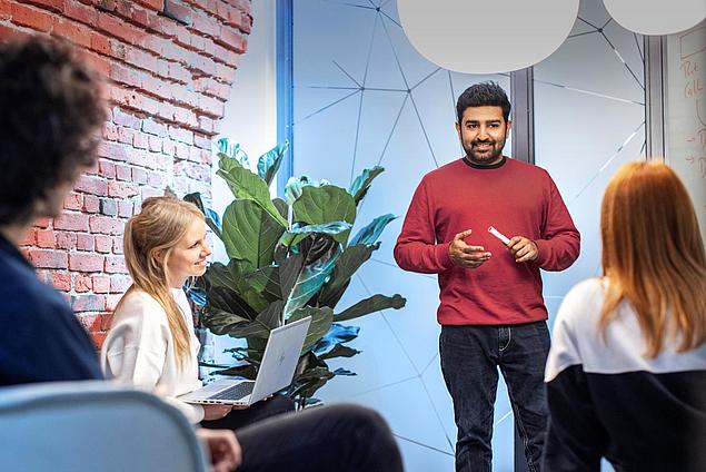 Employees in discussion at HHLA Next, the innovation unit of HHLA, in a modern meeting room.