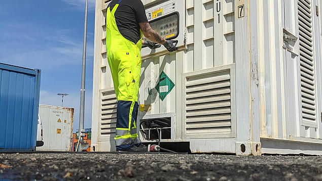HHLA-Service-Mitarbeiter bei der technischen Prüfung eines Kühlaggregats an einem weißen Reefer-Container.